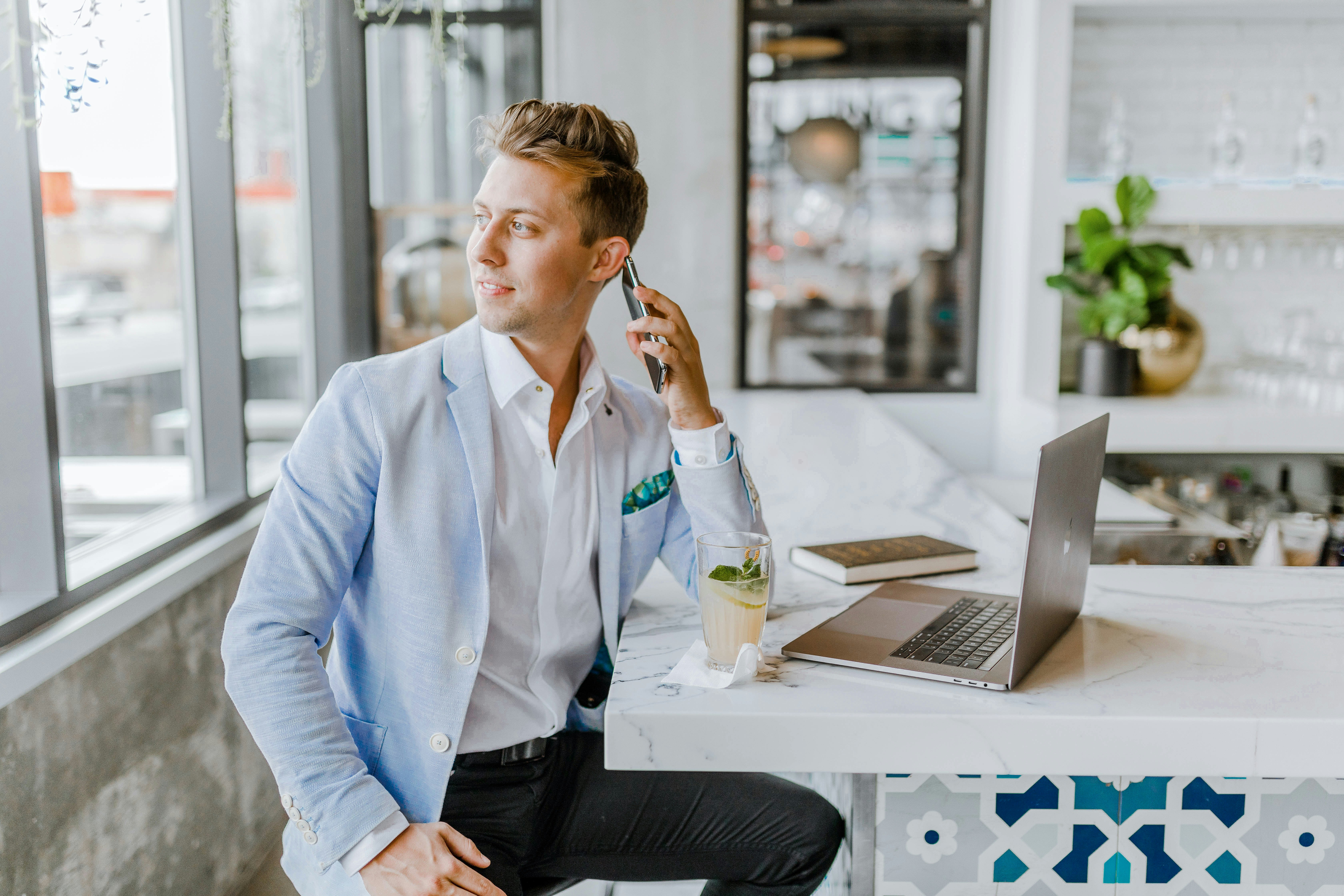 Entrepreneur taking a call at a café counter with a laptop