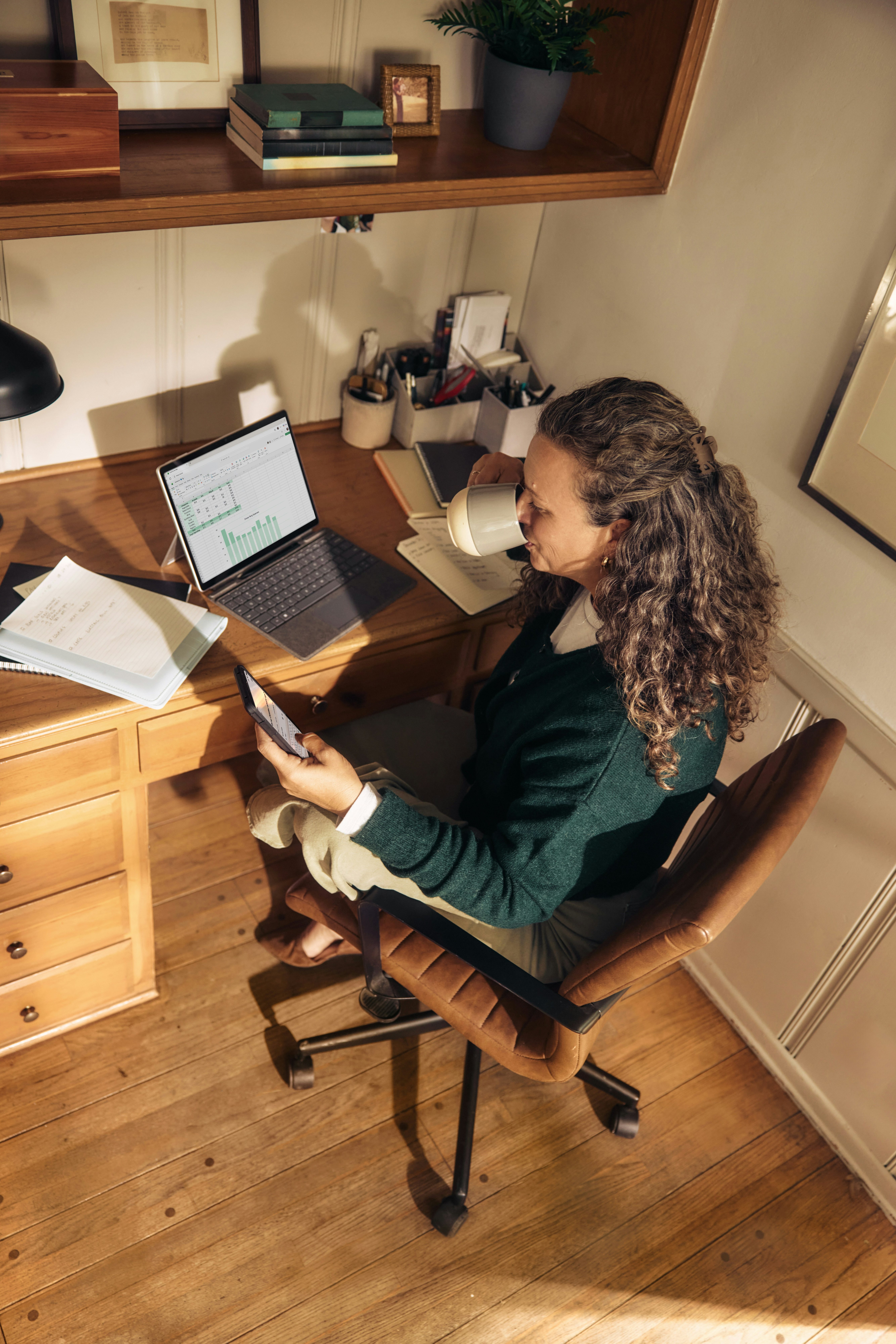 Professional working at a home office desk with laptop and notes